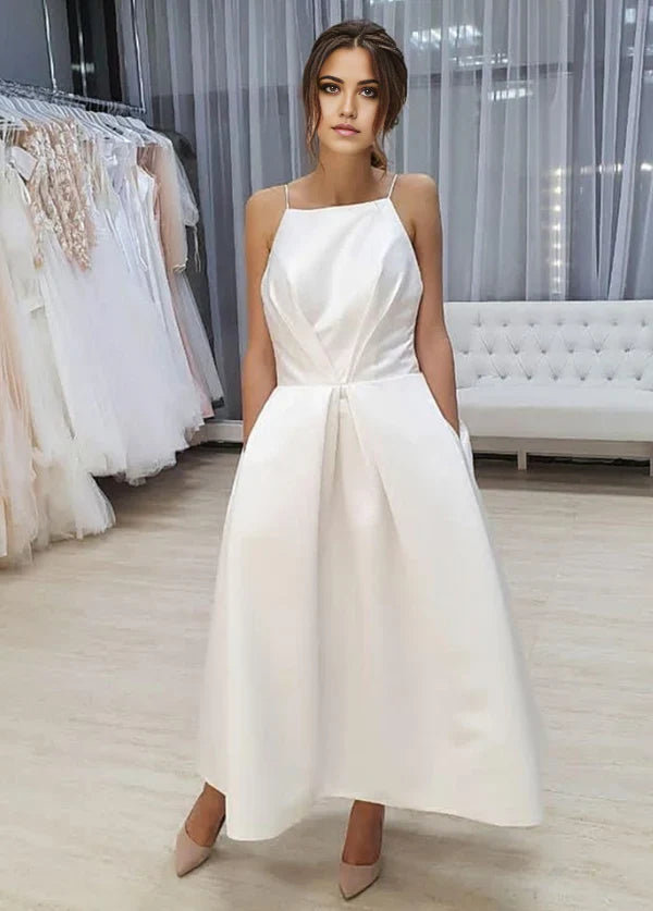 Vestido de novia sencillo de corte A, sin mangas, con tirantes finos, espalda abierta, largo hasta la rodilla y bolsillos